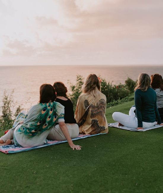 Women looking at the ocean in Kauai to enjoy the sunset at a retreat.