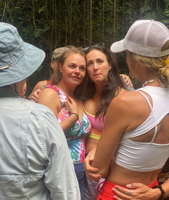 Women embracing and supporting one another during an emotional healing moment at a women's retreat in Kauai.