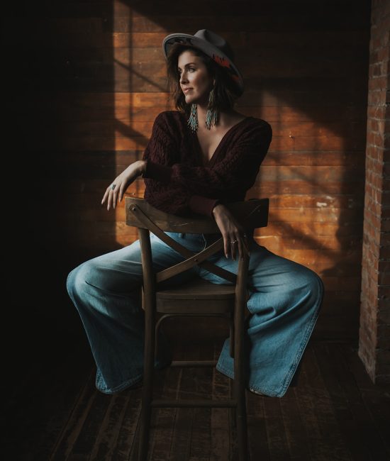 Woman in a room looking out a window branding photoshoot